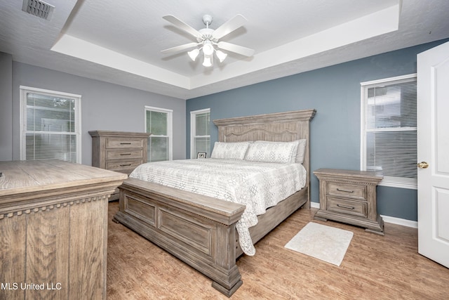 2204 Rue Beaux Chenes, Ocean Springs, MS 39564 - bedroom featuring a tray ceiling, light wood-style flooring, and a ceiling fan