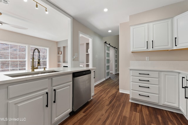 kitchen with sink, dishwasher, a barn door, and white cabinets