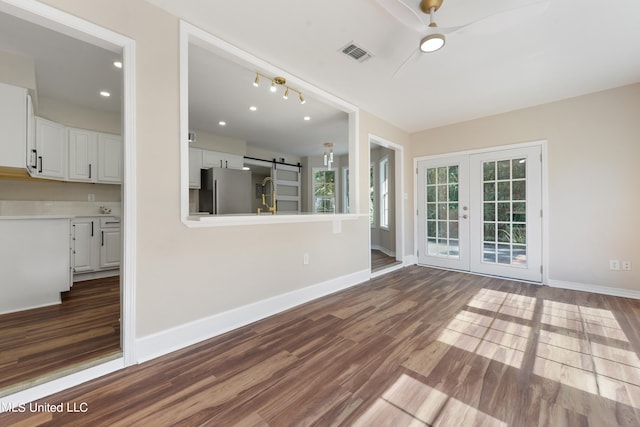 unfurnished living room with french doors, ceiling fan, dark hardwood / wood-style floors, and a barn door