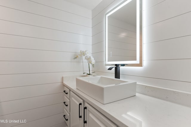 bathroom featuring vanity and wooden walls