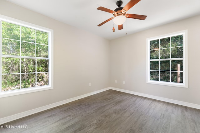 spare room featuring dark wood-type flooring, ceiling fan, and plenty of natural light