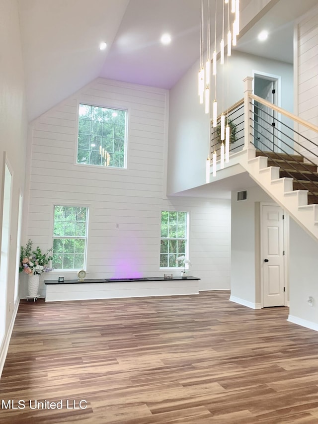 unfurnished living room featuring a healthy amount of sunlight, high vaulted ceiling, and wood-type flooring