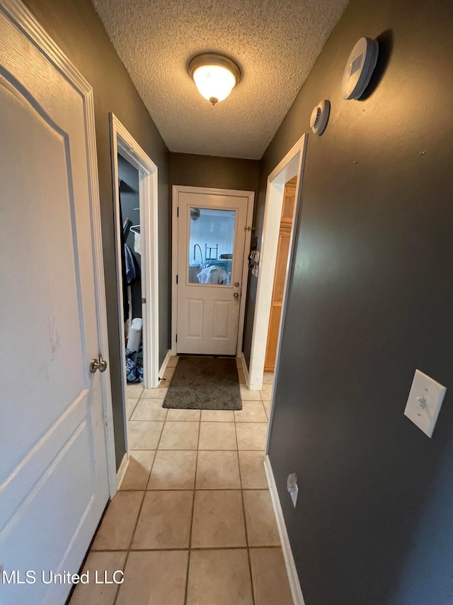 doorway with light tile patterned floors and a textured ceiling