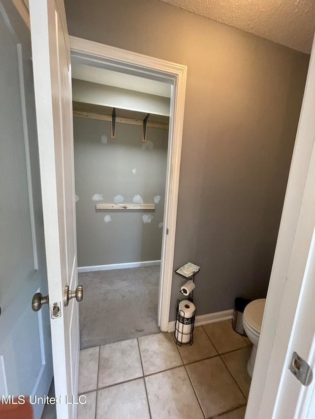 bathroom featuring a textured ceiling, tile patterned floors, and toilet