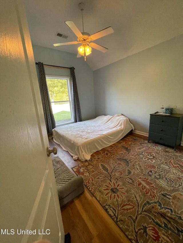 bedroom with ceiling fan, vaulted ceiling, and hardwood / wood-style floors