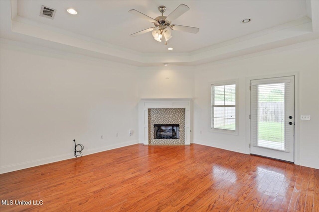 409 Sand Stone Pl, Brandon, MS 39042 - unfurnished living room with a raised ceiling, crown molding, light wood-type flooring, a ceiling fan, and a tiled fireplace