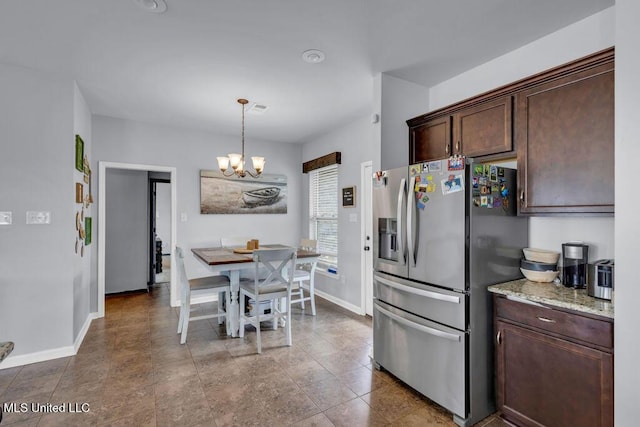 16904 Desmare St, Gulfport, MS 39503 - kitchen with stainless steel fridge with ice dispenser, dark brown cabinetry, a chandelier, decorative light fixtures, and light stone counters