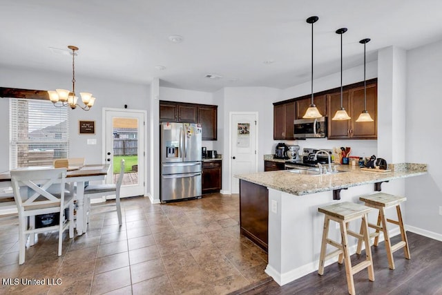 16904 Desmare St, Gulfport, MS 39503 - kitchen with appliances with stainless steel finishes, a chandelier, a peninsula, dark brown cabinetry, and light stone counters