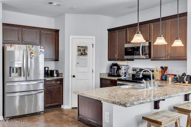 16904 Desmare St, Gulfport, MS 39503 - kitchen featuring appliances with stainless steel finishes, a peninsula, dark brown cabinetry, light stone counters, and hanging light fixtures