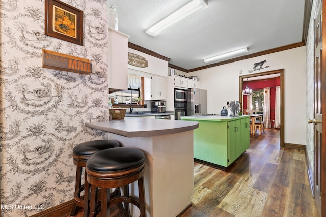 kitchen with kitchen peninsula, white cabinets, a breakfast bar, ornamental molding, and dark hardwood / wood-style floors