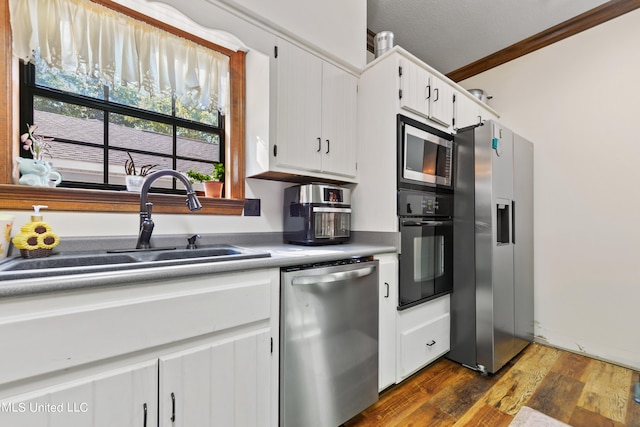 kitchen featuring white cabinets, dark hardwood / wood-style flooring, appliances with stainless steel finishes, ornamental molding, and sink