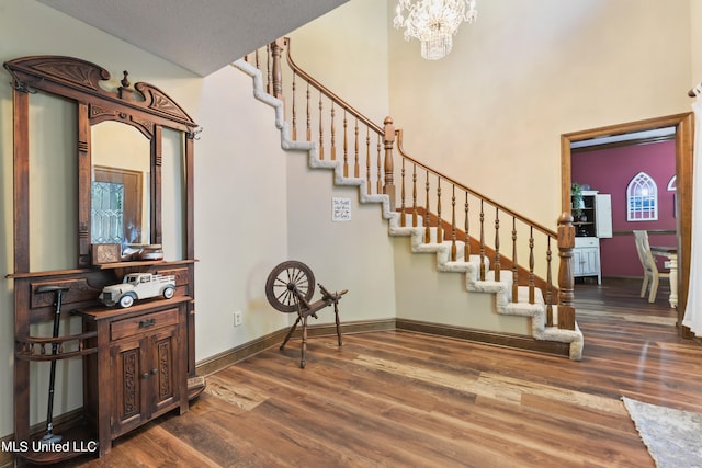 stairway with a notable chandelier, a high ceiling, and hardwood / wood-style floors