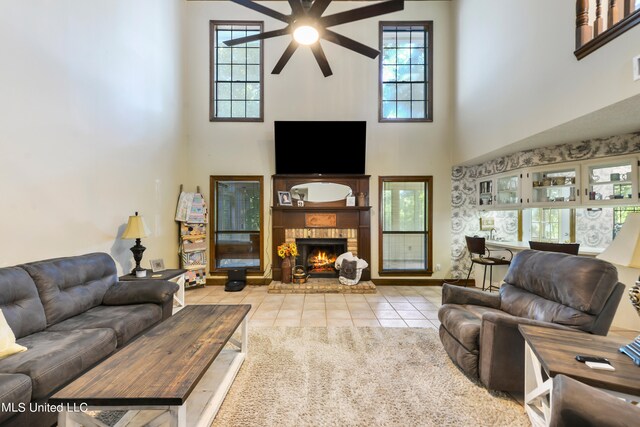 tiled living room with a towering ceiling, a brick fireplace, and plenty of natural light