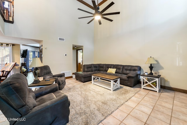 living room with a towering ceiling, ceiling fan, and light tile patterned floors