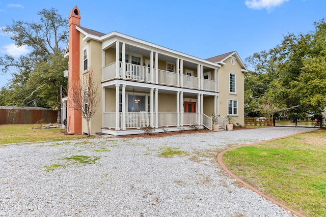 view of front facade with a front lawn, a balcony, and a porch