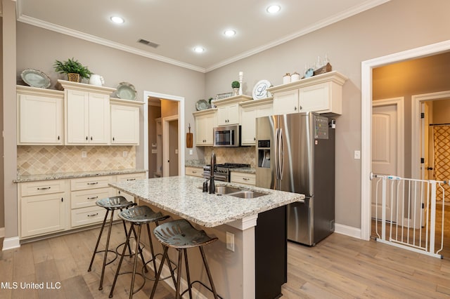 kitchen with light stone counters, cream cabinetry, stainless steel appliances, and backsplash