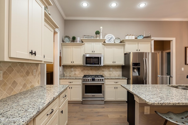 kitchen with appliances with stainless steel finishes, cream cabinets, ornamental molding, decorative backsplash, and light wood-type flooring