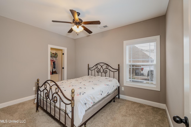 bedroom featuring a spacious closet, light carpet, ceiling fan, and a closet