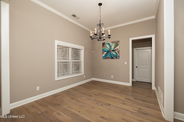 empty room featuring wood-type flooring, ornamental molding, and an inviting chandelier