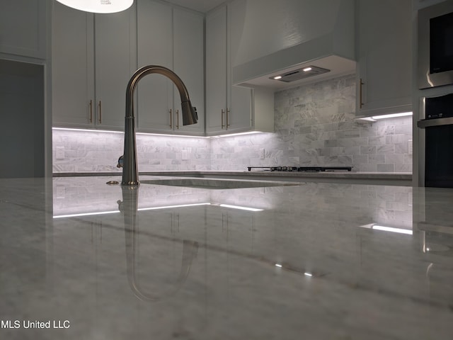 kitchen with custom range hood, stainless steel appliances, and tasteful backsplash