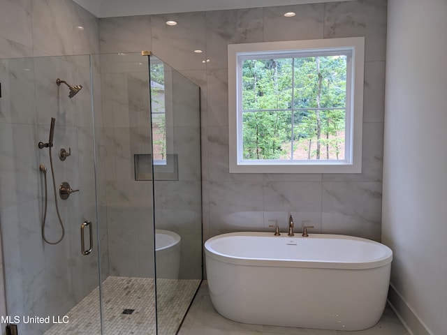 bathroom with a wealth of natural light, tile walls, and shower with separate bathtub