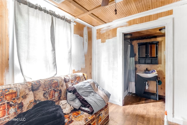 interior space with ceiling fan, wood walls, wooden ceiling, and hardwood / wood-style floors