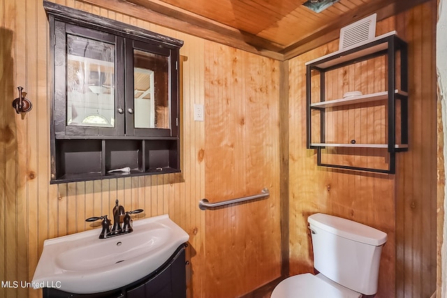 bathroom with wooden ceiling, vanity, toilet, and wood walls