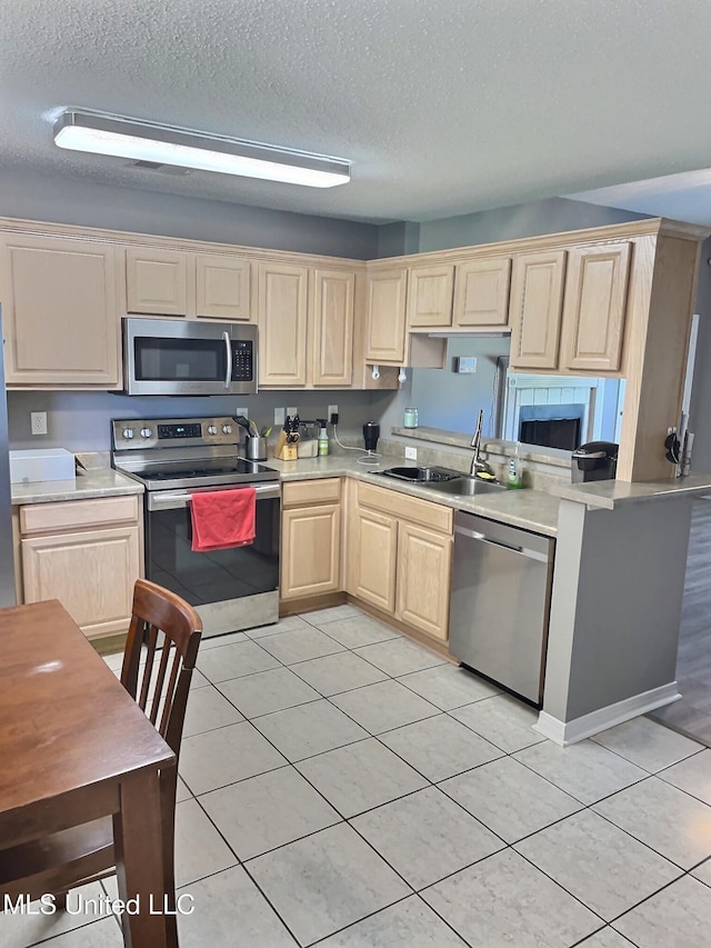 8617 Pinoak Ln, Ocean Springs, MS 39564 - kitchen featuring appliances with stainless steel finishes, light brown cabinets, light tile patterned floors, a textured ceiling, and light countertops
