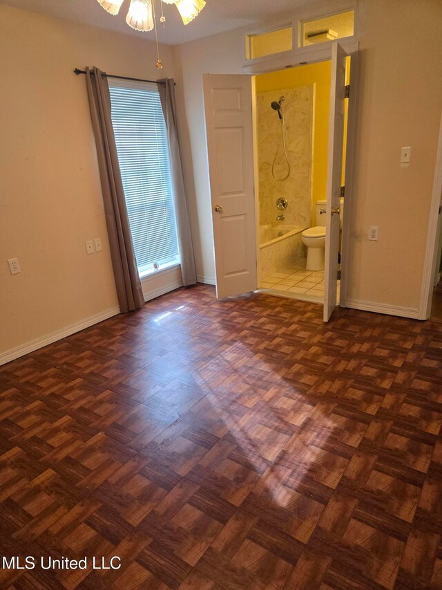 unfurnished bedroom featuring ensuite bathroom and dark parquet floors