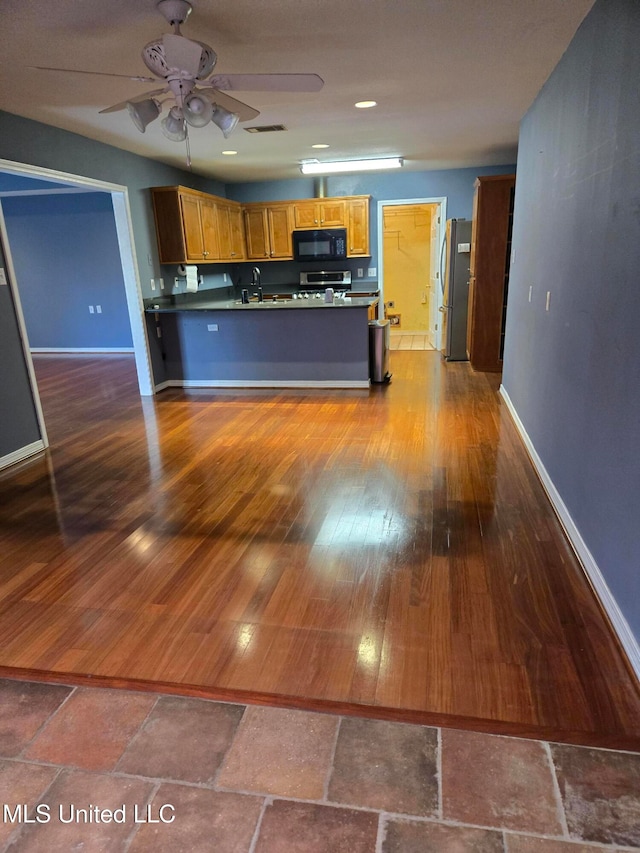 kitchen with kitchen peninsula, stainless steel fridge, dark hardwood / wood-style flooring, and ceiling fan