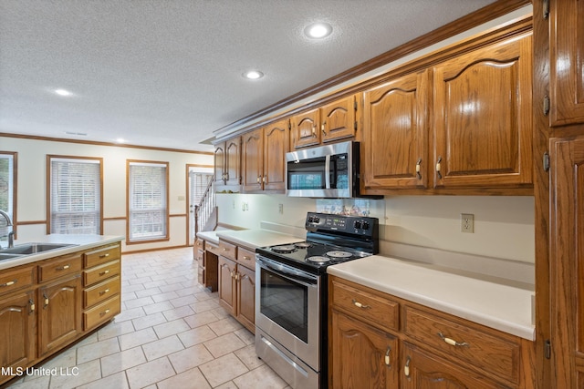 kitchen with sink, stainless steel appliances, a textured ceiling, light tile patterned flooring, and ornamental molding