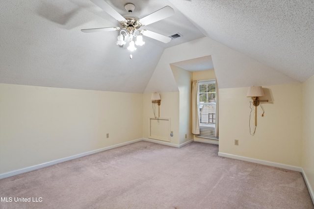 additional living space featuring a textured ceiling, ceiling fan, lofted ceiling, and light carpet