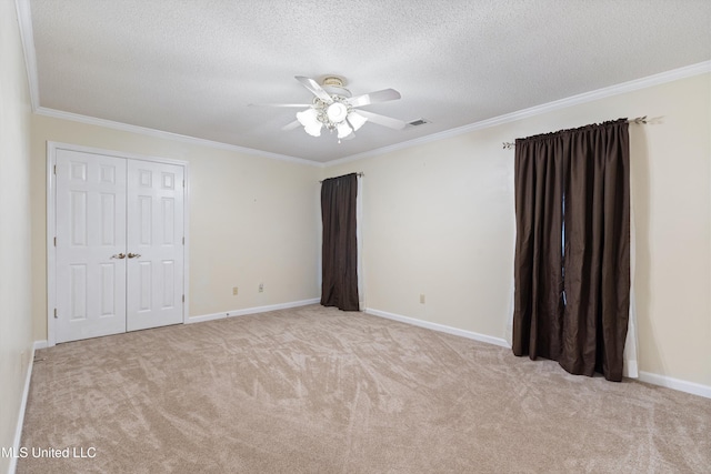 carpeted spare room featuring a textured ceiling, ceiling fan, and ornamental molding