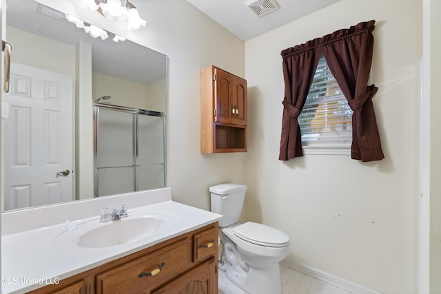 bathroom with vanity, toilet, a shower with door, and a textured ceiling