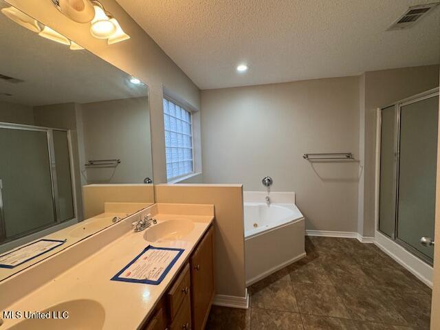 bathroom featuring double vanity, visible vents, a bath, a textured ceiling, and a sink