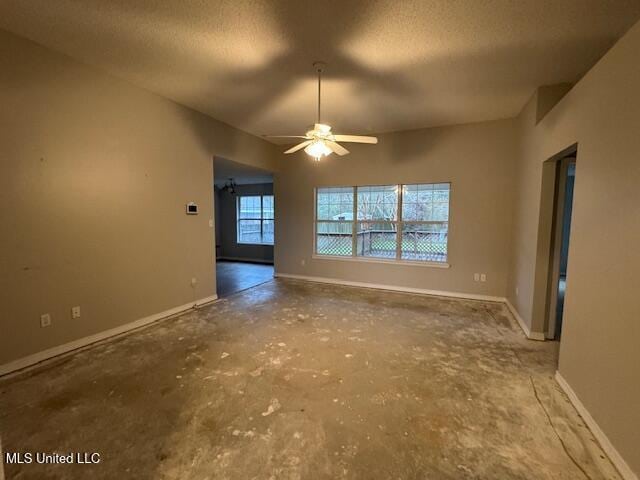 unfurnished living room with a textured ceiling, ceiling fan, and baseboards