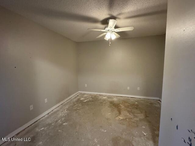 spare room with a ceiling fan, concrete floors, a textured ceiling, and baseboards