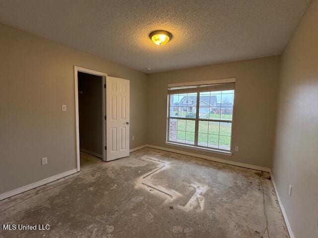 unfurnished bedroom with a textured ceiling and baseboards