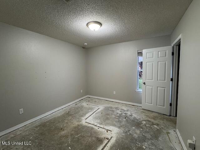 spare room with baseboards and a textured ceiling