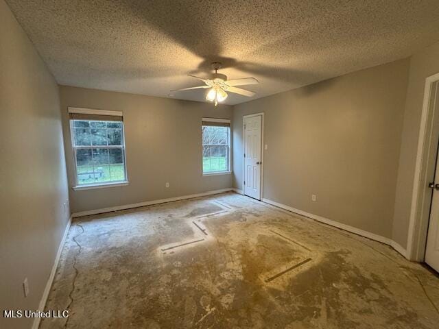 interior space featuring plenty of natural light, a textured ceiling, baseboards, and ceiling fan