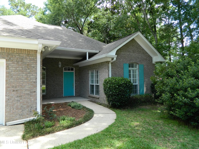 7890 Hilo Way, Diamondhead, MS 39525 - entrance to property with roof with shingles, brick siding, and a lawn