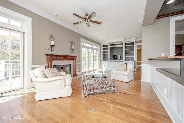 1401 Ladnier Rd, Gautier, MS 39553 - living room with a high end fireplace, ornamental molding, ceiling fan, built in shelves, and light wood-style floors