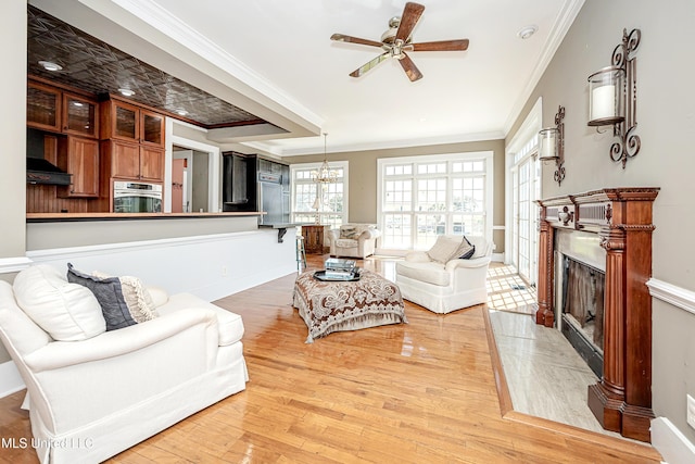 1401 Ladnier Rd, Gautier, MS 39553 - living room featuring crown molding, light wood-style floors, a premium fireplace, and ceiling fan with notable chandelier