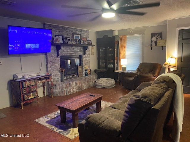 living room featuring a brick fireplace, tile patterned floors, a textured ceiling, ornamental molding, and ceiling fan