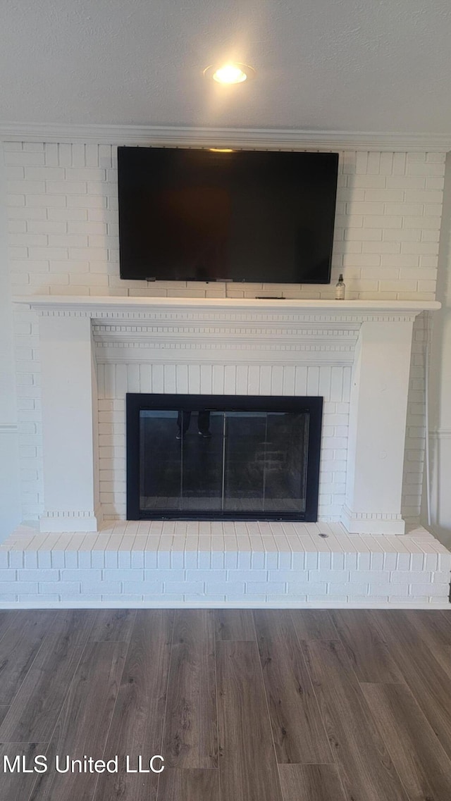 interior details featuring hardwood / wood-style flooring, a textured ceiling, and a brick fireplace