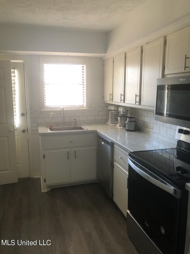 kitchen with dark wood-type flooring, sink, decorative backsplash, appliances with stainless steel finishes, and white cabinetry