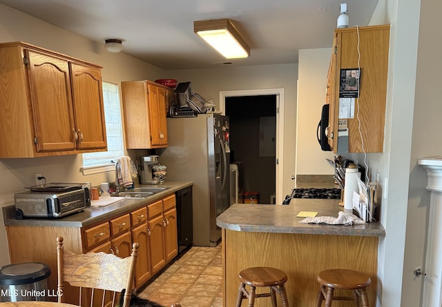 kitchen featuring a sink, a toaster, a peninsula, a kitchen bar, and black appliances