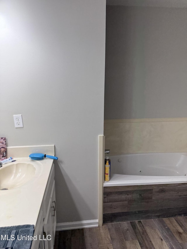 full bath with vanity, a whirlpool tub, and wood finished floors