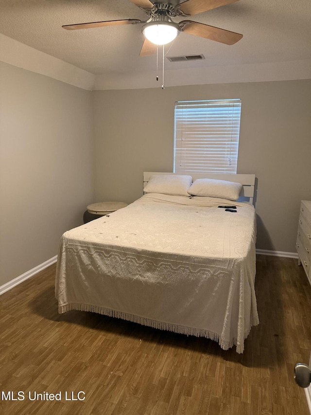bedroom with visible vents, a ceiling fan, baseboards, and wood finished floors