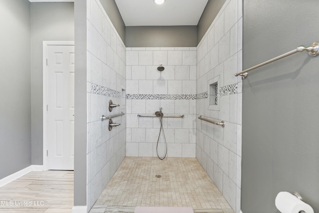 bathroom featuring hardwood / wood-style floors and a tile shower